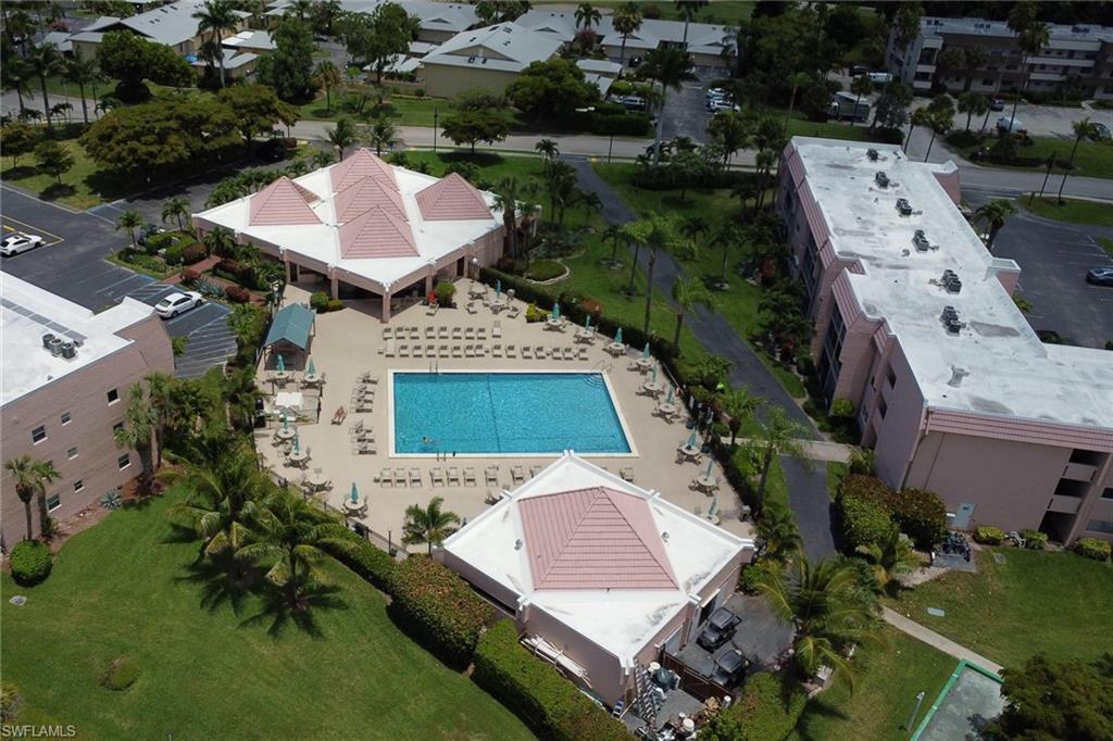 Expansive outdoor common area featuring a rectangular swimming pool, surrounding paved patio, and multiple lounge chairs
