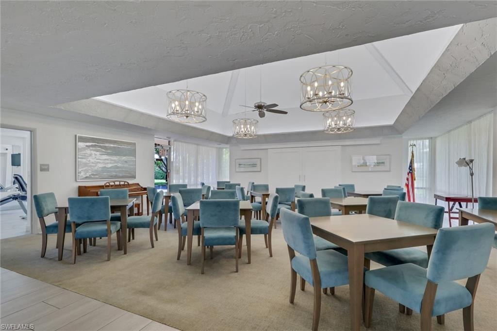 Spacious common area featuring a vaulted ceiling with skylight, recessed lighting, and multiple decorative chandeliers