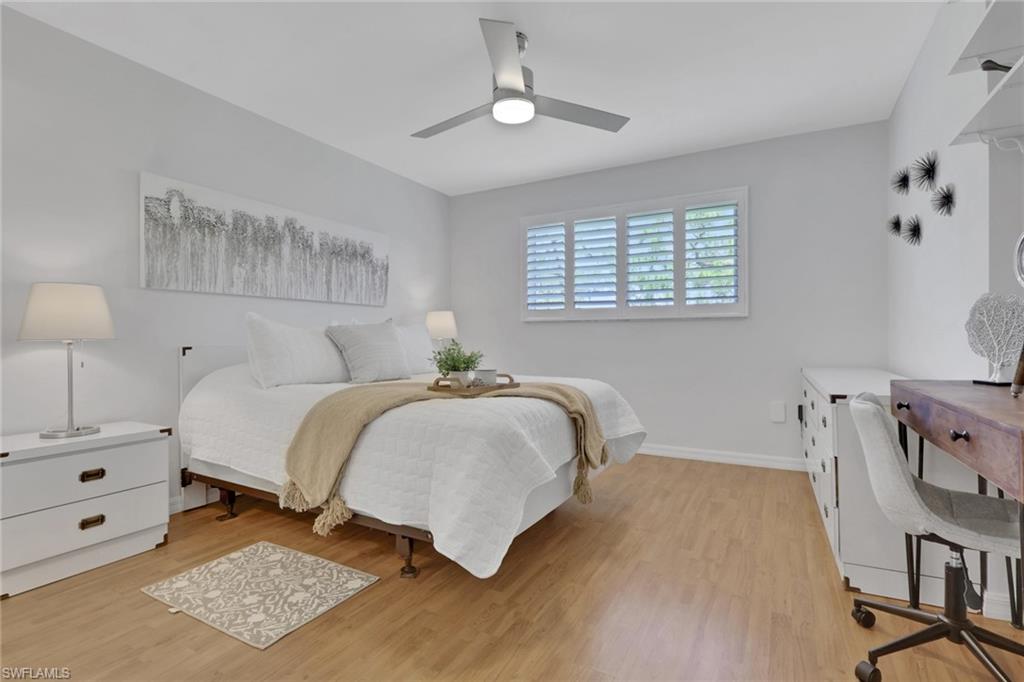 Bright interior space featuring wood-finish flooring, a contemporary ceiling fan with integrated lighting, and white plantation shutters