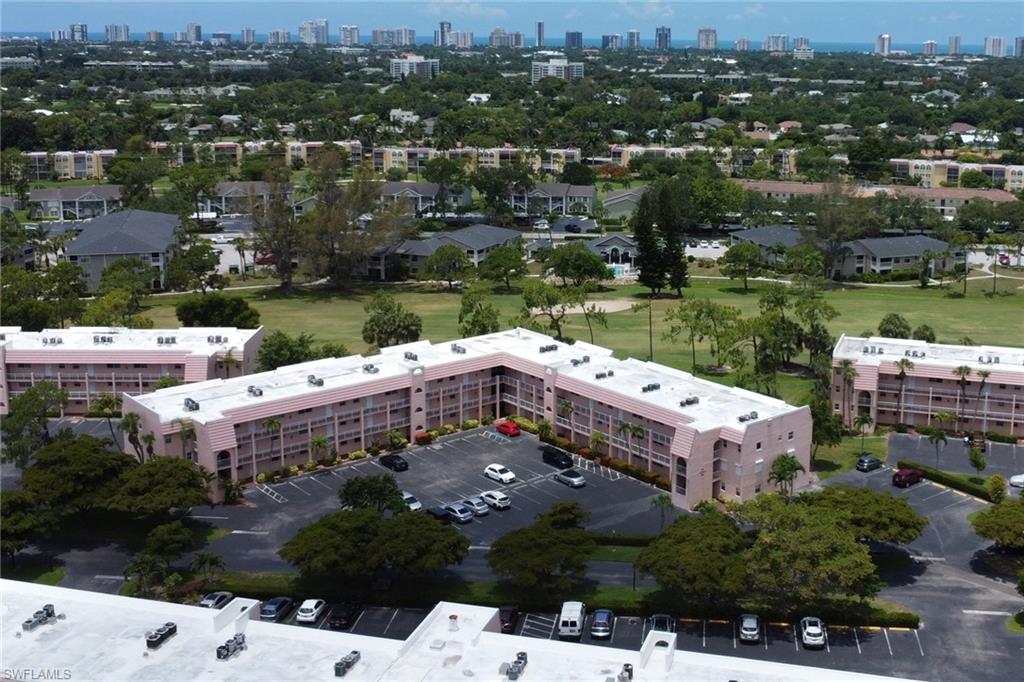 Expansive residential complex featuring multiple buildings with private balconies, ample surface parking, surrounded by mature trees and manicured green spaces