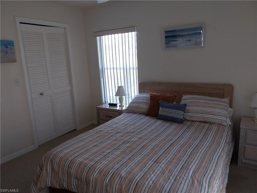 Carpeted bedroom with a closet and baseboards