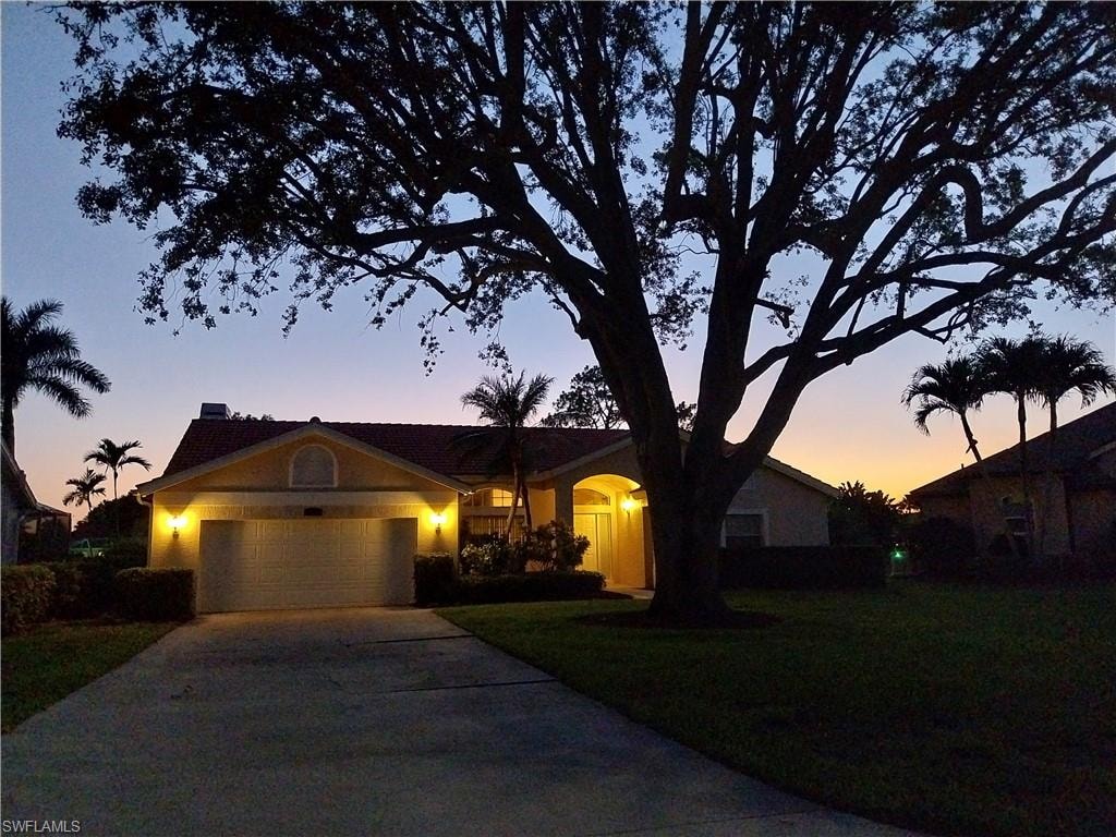 Ranch-style house featuring an attached garage, driveway, a front yard, and stucco siding