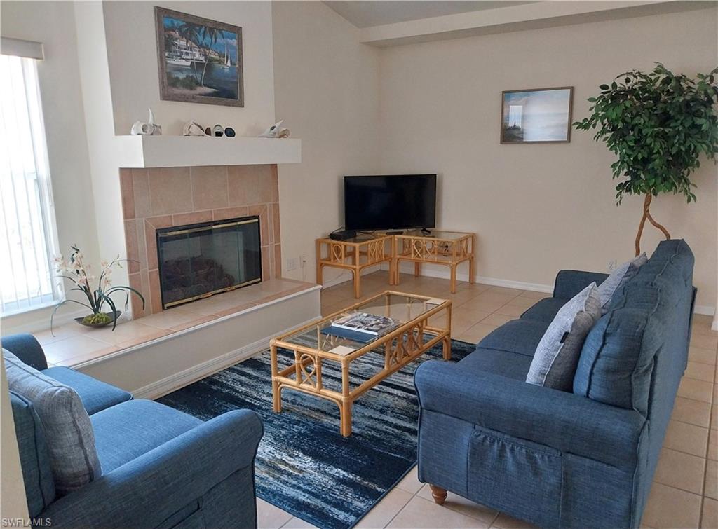 Living room with tile patterned floors and a tiled fireplace