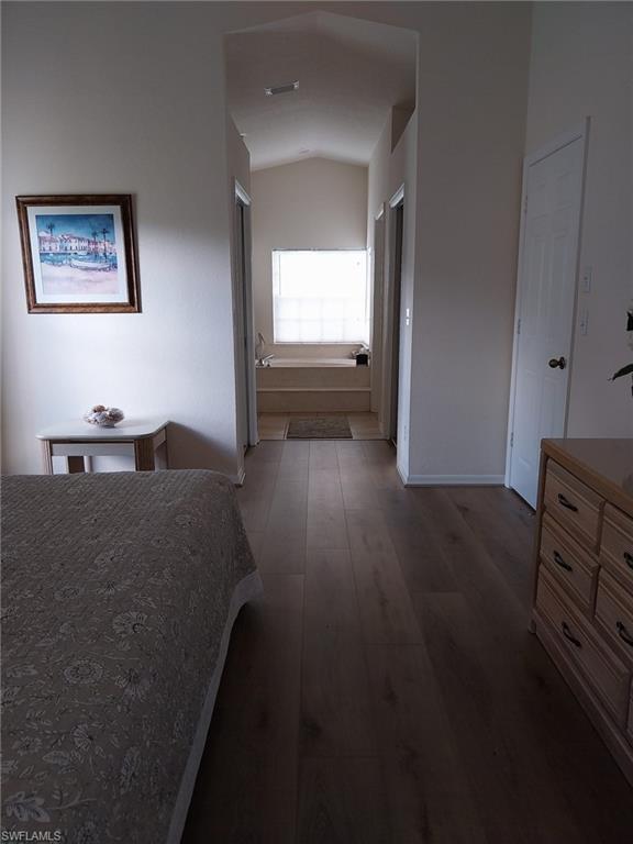 Bedroom featuring dark wood-style floors and lofted ceiling