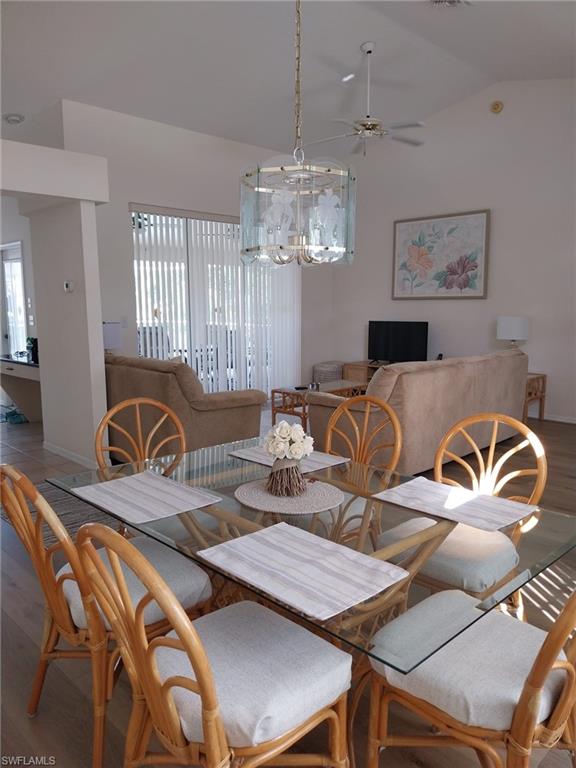 Dining space featuring wood finished floors, vaulted ceiling, and a ceiling fan