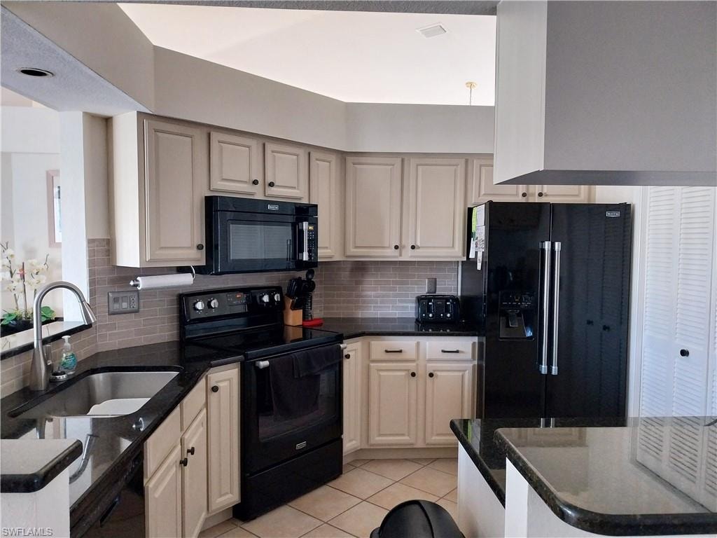 Kitchen featuring black appliances, tasteful backsplash, and light tile patterned flooring