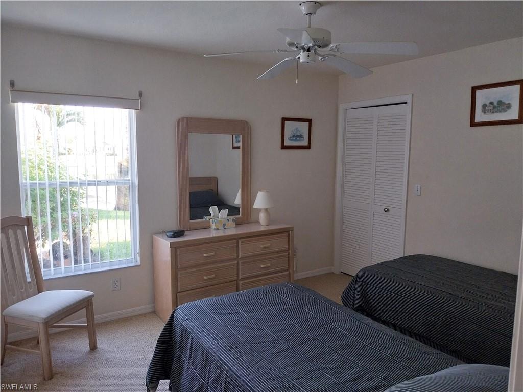 Bedroom featuring light colored carpet, ceiling fan, and a closet