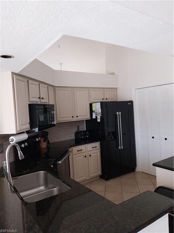 Kitchen featuring fridge, backsplash, light tile patterned flooring, a textured ceiling, and range