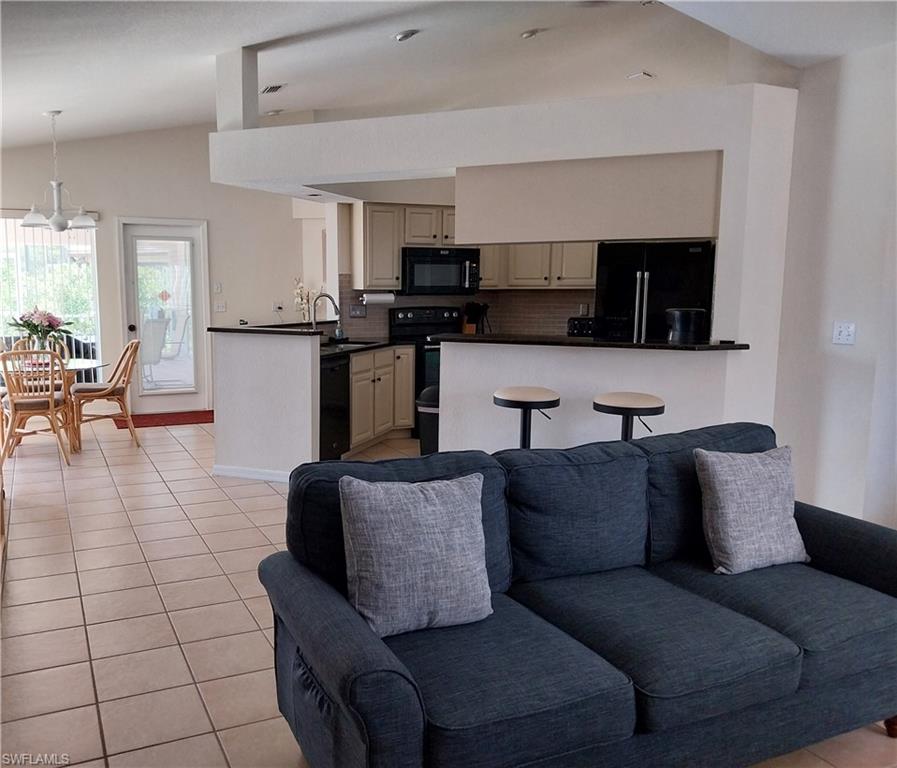 Living room with light tile patterned floors and lofted ceiling