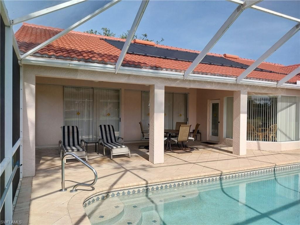 Swimming pool with a patio area, glass enclosure, and outdoor dining area