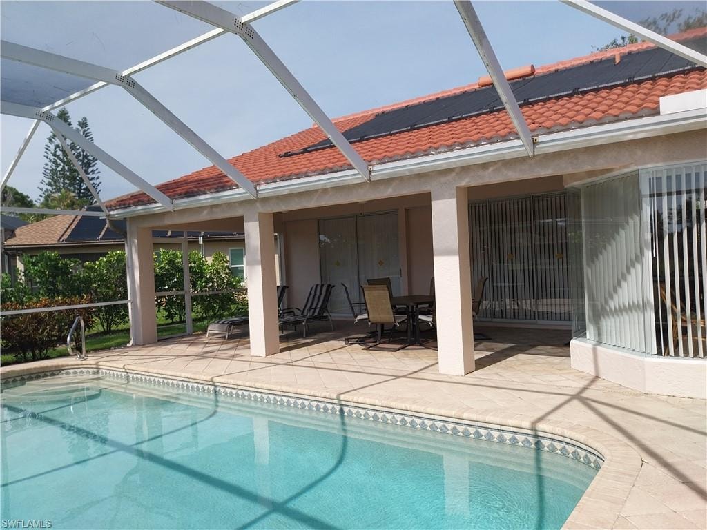 Swimming pool with a patio area, glass enclosure, and outdoor dining area