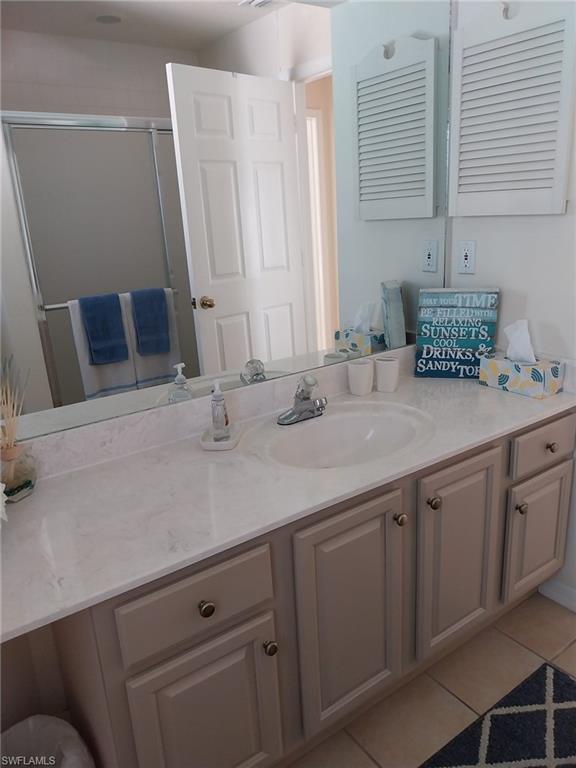 Full bathroom with light tile patterned floors, vanity, and a shower stall