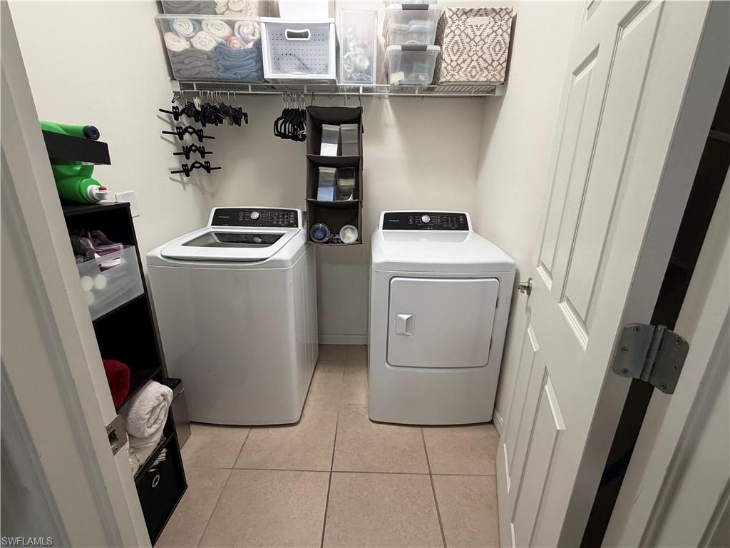 Laundry area featuring a top-load washing machine, a front-load dryer, tiled flooring, and overhead wire shelving