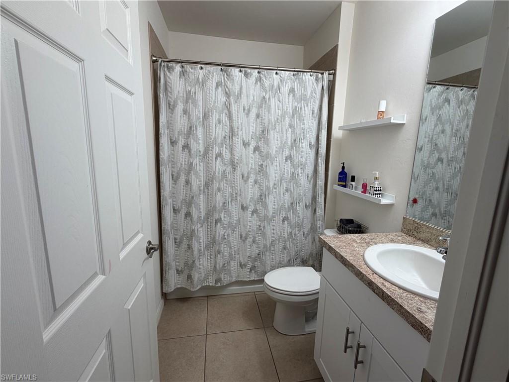Bathroom featuring a full vanity with a granite-style countertop, undermount sink, and white cabinetry