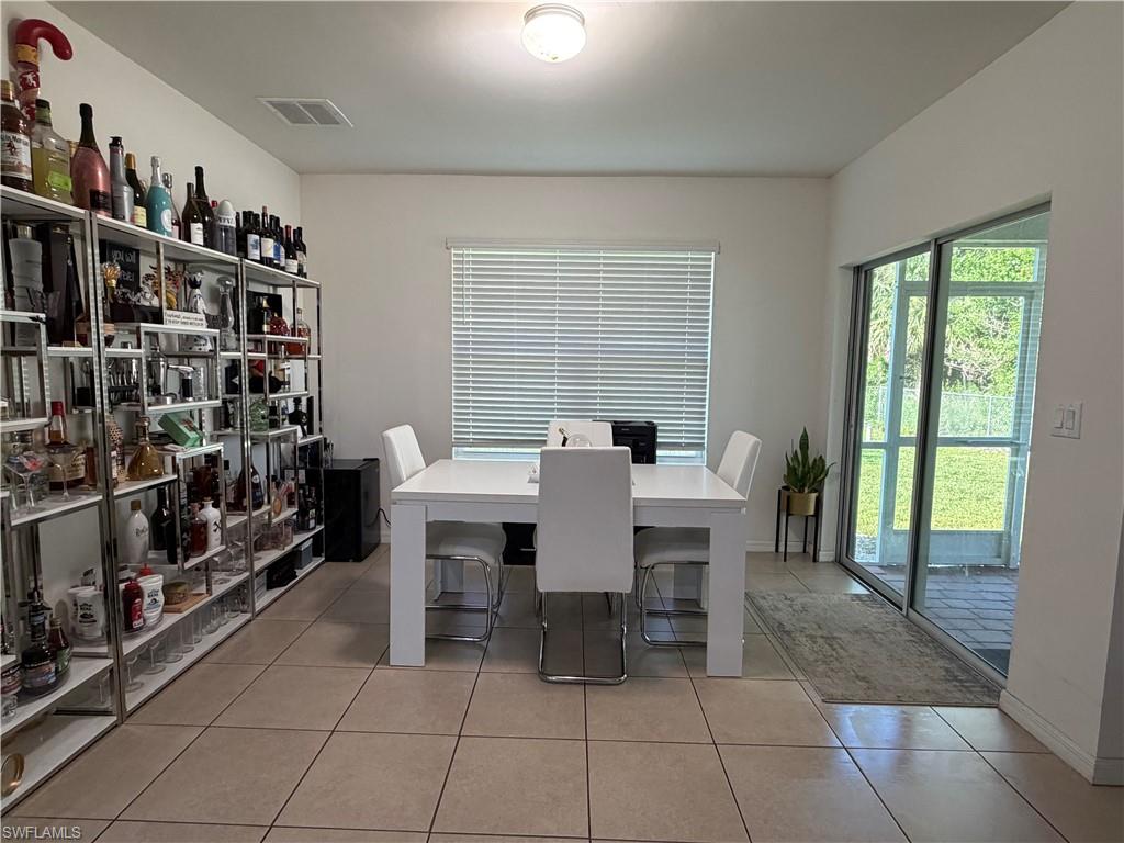 Dining area featuring tile flooring, a large window with blinds, and sliding glass doors to the exterior