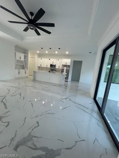 Unfurnished living room featuring light marble finish flooring, recessed lighting, and a raised ceiling