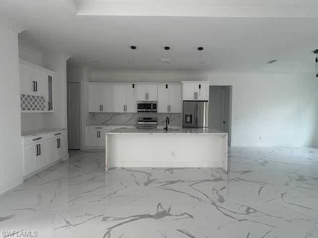 Kitchen with a center island with sink, light stone counters, white cabinets, appliances with stainless steel finishes, and light marble finish floors