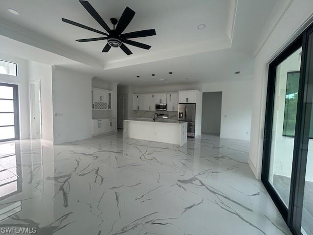 Unfurnished living room with light marble finish flooring, a raised ceiling, ceiling fan, and recessed lighting