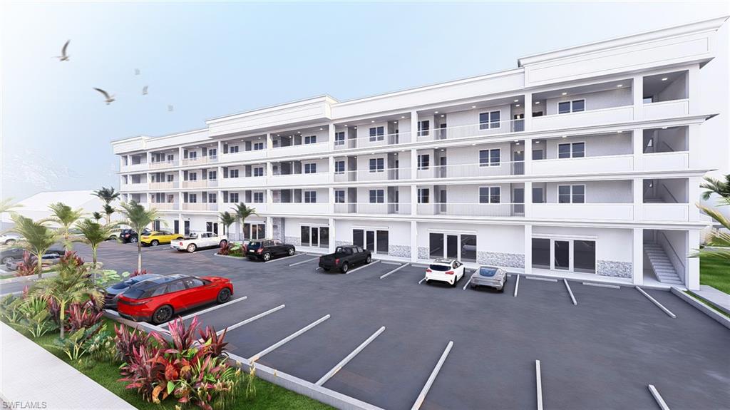 View of apartment building / complex featuring uncovered parking