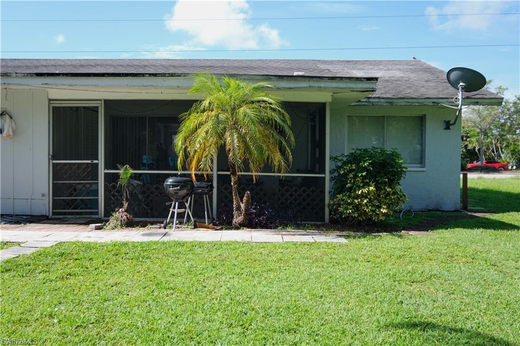 Single-story exterior featuring a screened patio area, a mature palm tree, and a shrub