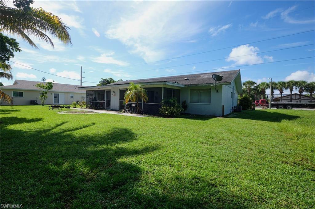 Expansive green lawn surrounds the property, featuring a screened-in patio area and a visible air conditioning unit