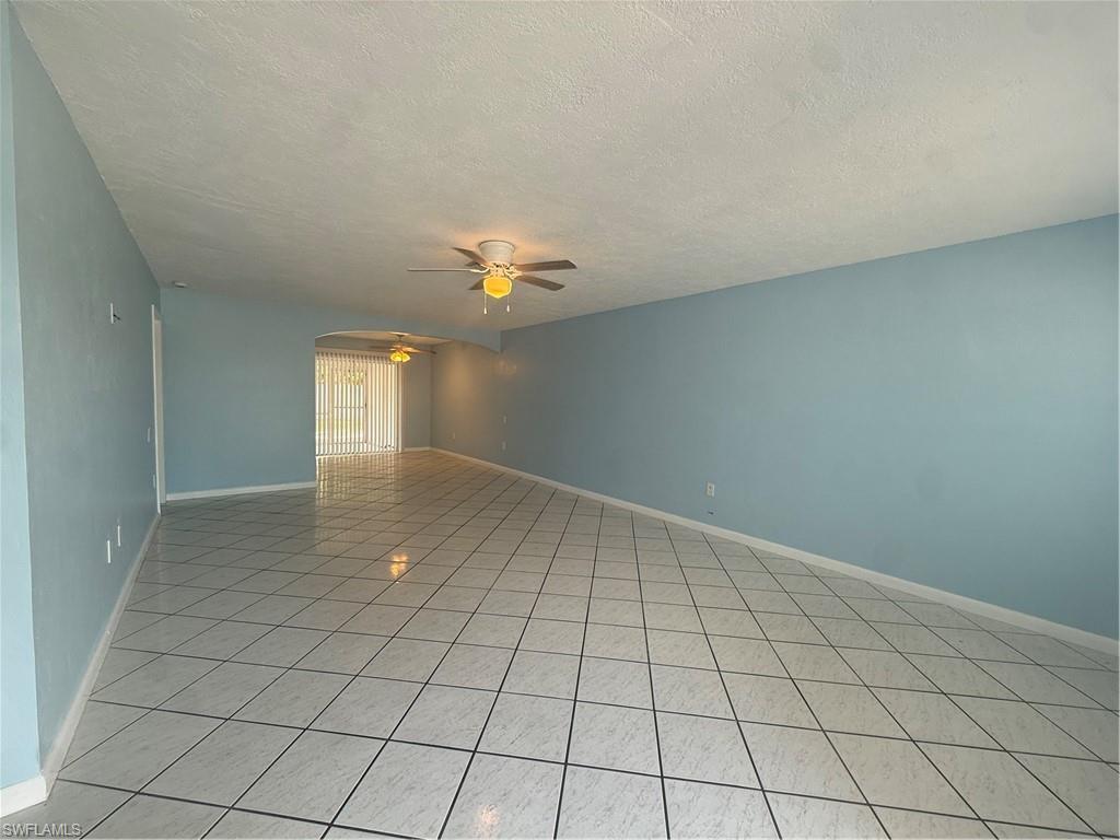 Spacious interior with tile flooring throughout, light blue wall paint, and multiple ceiling fans