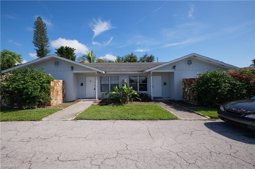 Duplex exterior featuring two entry doors, mature landscaping, and a low-pitch roofline
