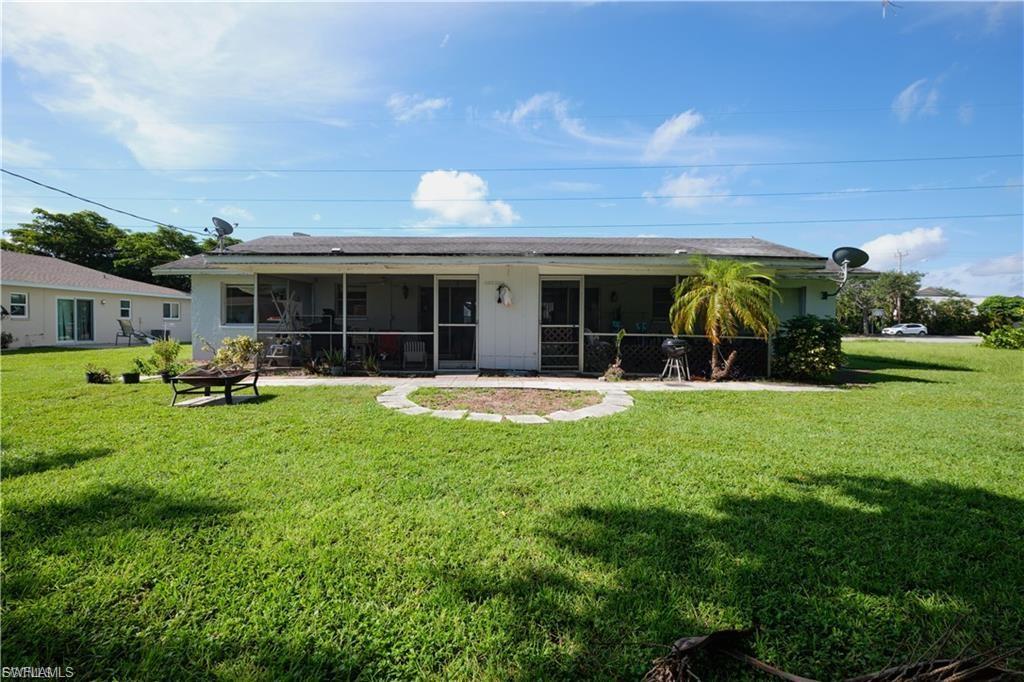 Expansive rear yard featuring a screened patio, a curved stepping stone pathway, and a mature palm tree