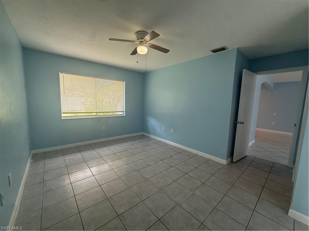 Spacious room featuring tile flooring, a ceiling fan with integrated lighting, a large window with horizontal blinds, and a doorway opening to an additional interior space