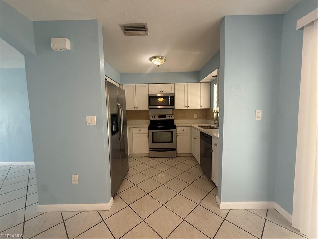 Kitchen featuring white cabinetry with brushed nickel hardware, stainless steel appliances, and a tile backsplash
