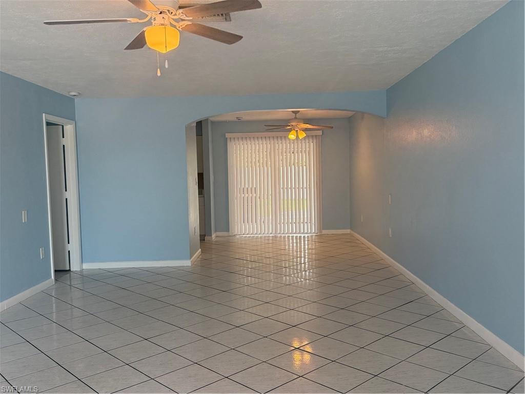 Spacious interior featuring light blue walls, diagonal tile flooring, and multiple ceiling fans