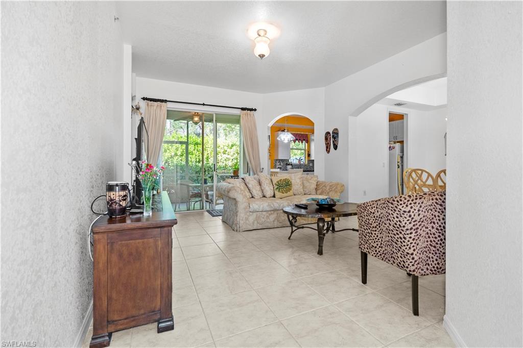 Living area with a textured wall, arched walkways, and light tile patterned flooring