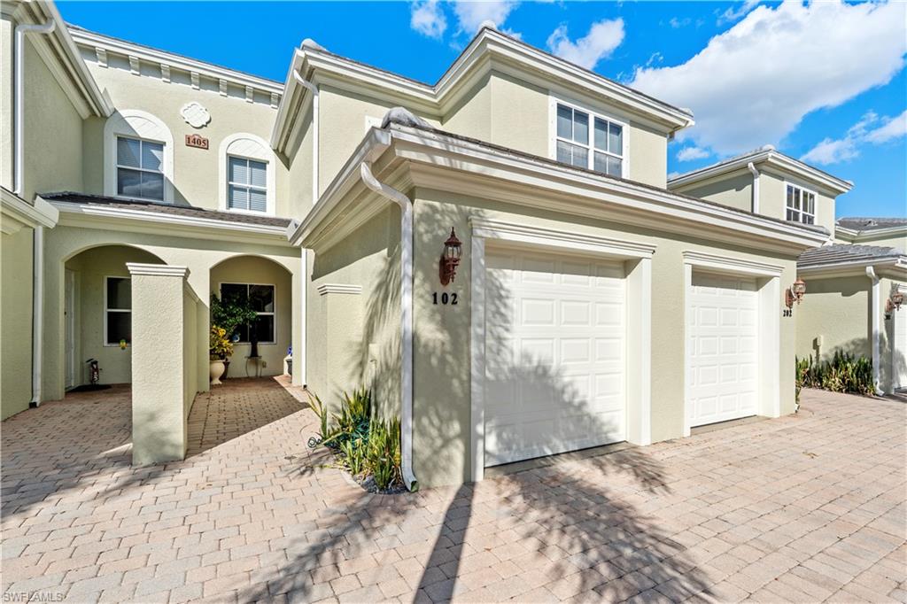 View of front of home with stucco siding, a garage, and decorative driveway