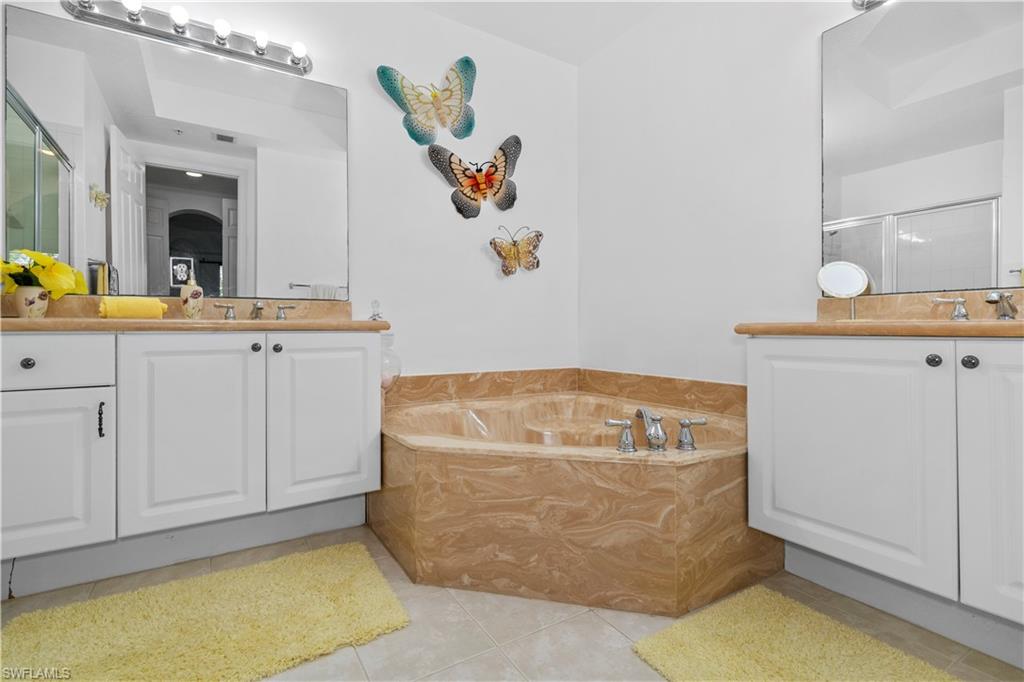 Bathroom with two vanities, a bath, a shower stall, and light tile patterned flooring
