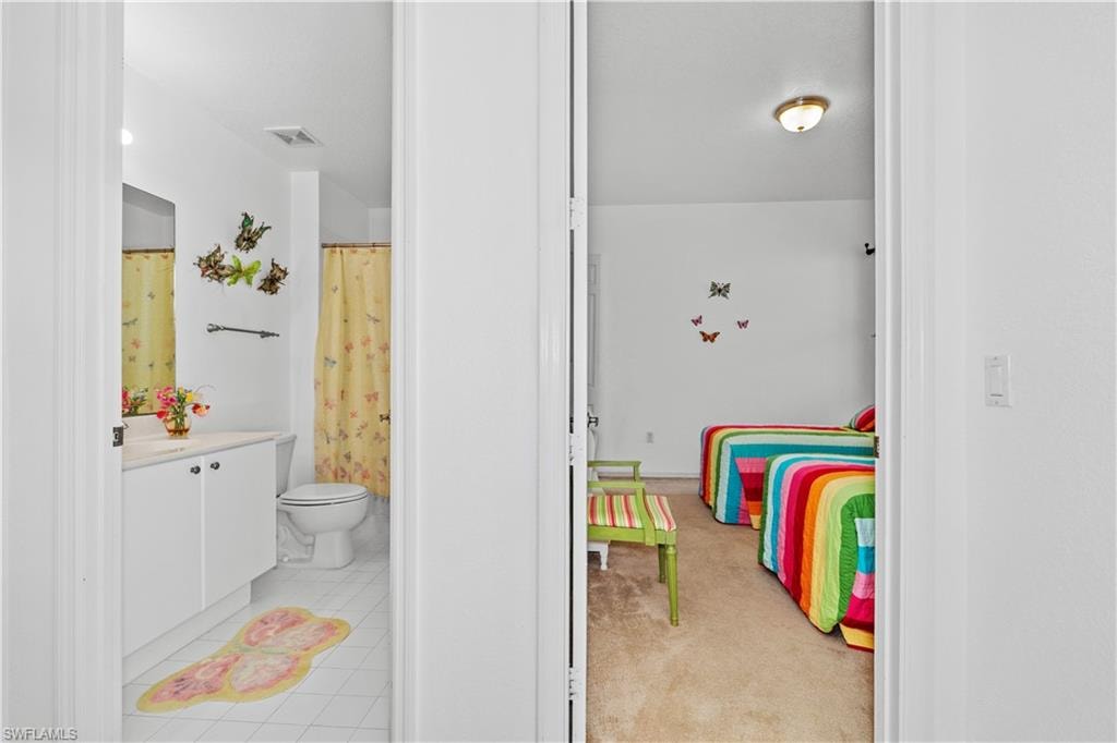 Full bathroom featuring vanity, a shower with curtain, light colored carpet, and light tile patterned floors