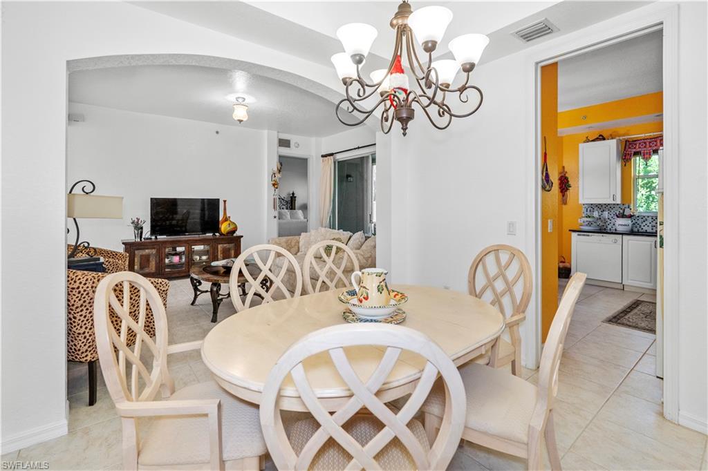 Dining space featuring arched walkways, a chandelier, and light tile patterned floors