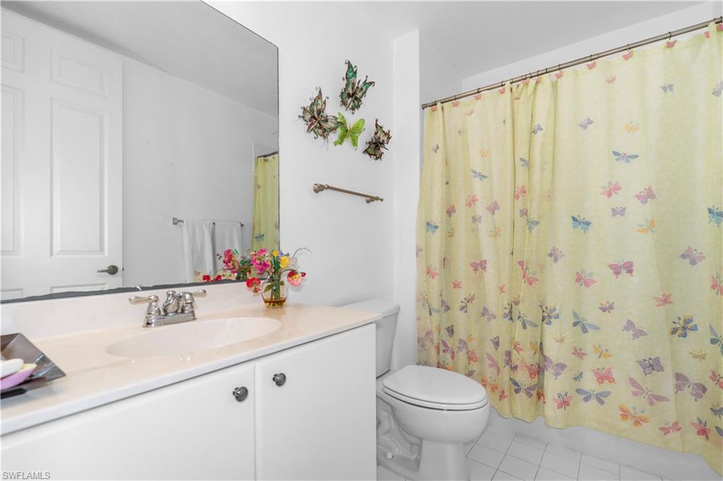 Full bath featuring vanity, light tile patterned flooring, and shower / bath combo