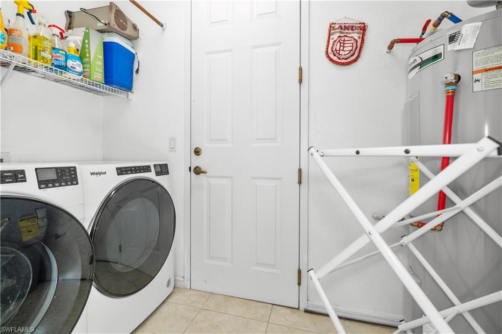 Laundry room featuring tile patterned floors, water heater, and washer and dryer