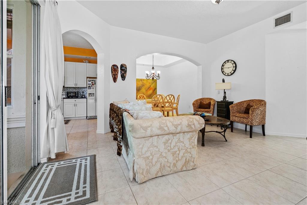 Living area with a chandelier, arched walkways, and light tile patterned floors
