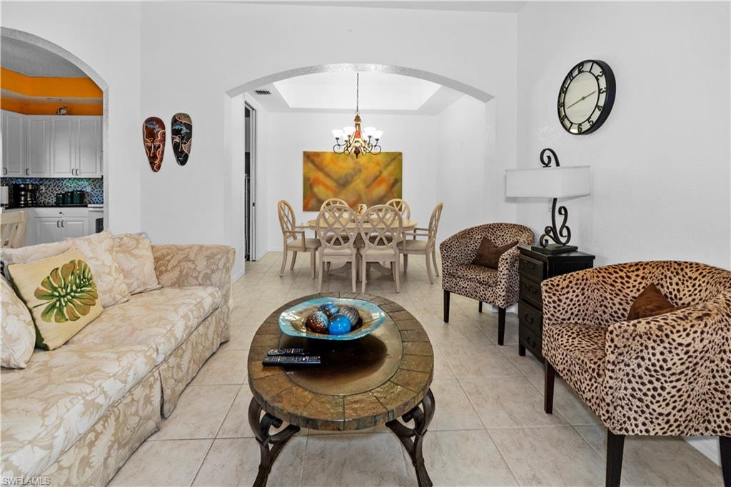 Living area with arched walkways, light tile patterned floors, and a chandelier
