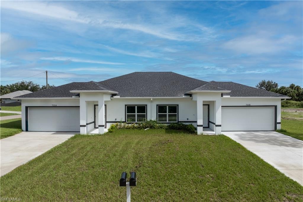Prairie-style home with a front yard, a garage, and roof with shingles