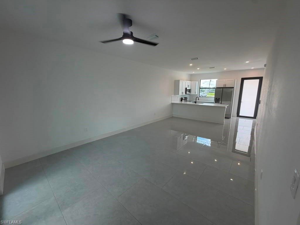 Spacious open-concept living area featuring large format tile flooring and a modern ceiling fan