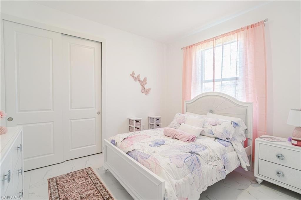 Room featuring white walls, white panel sliding closet doors, a window, and light-toned flooring