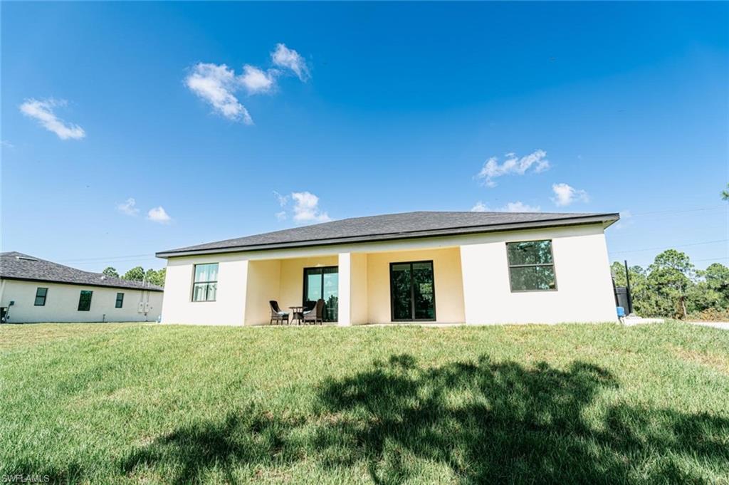 Rear exterior featuring a covered patio, sliding glass doors, and multiple windows