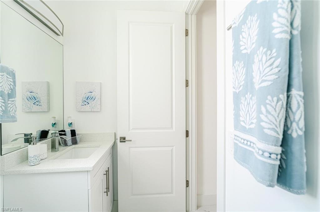 White vanity with shaker-style cabinetry, an integrated sink, and a light-toned countertop