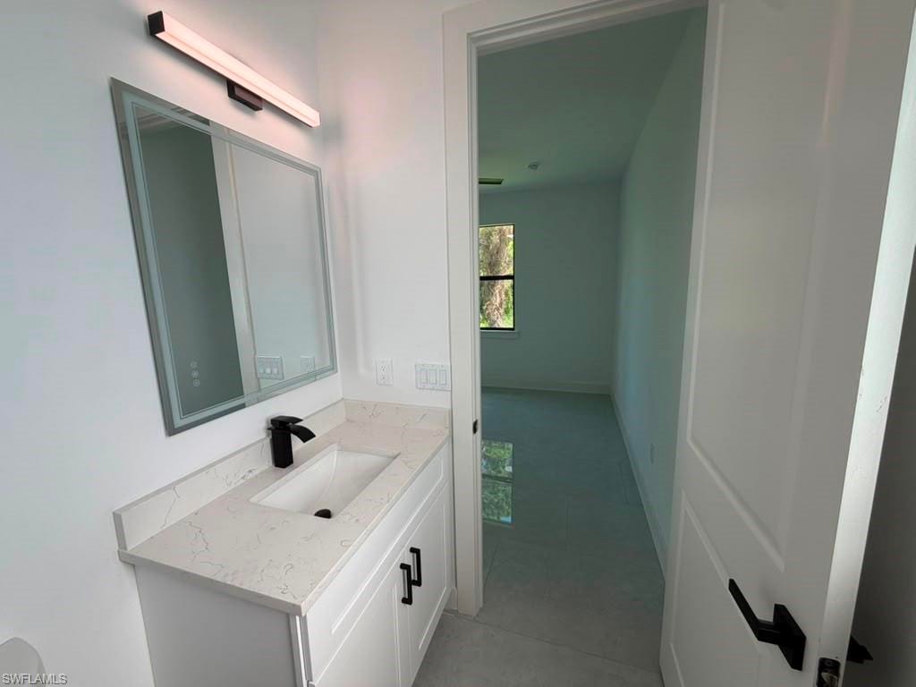 Bathroom vanity featuring a quartz-finish countertop, under-mount sink, and matte black faucet