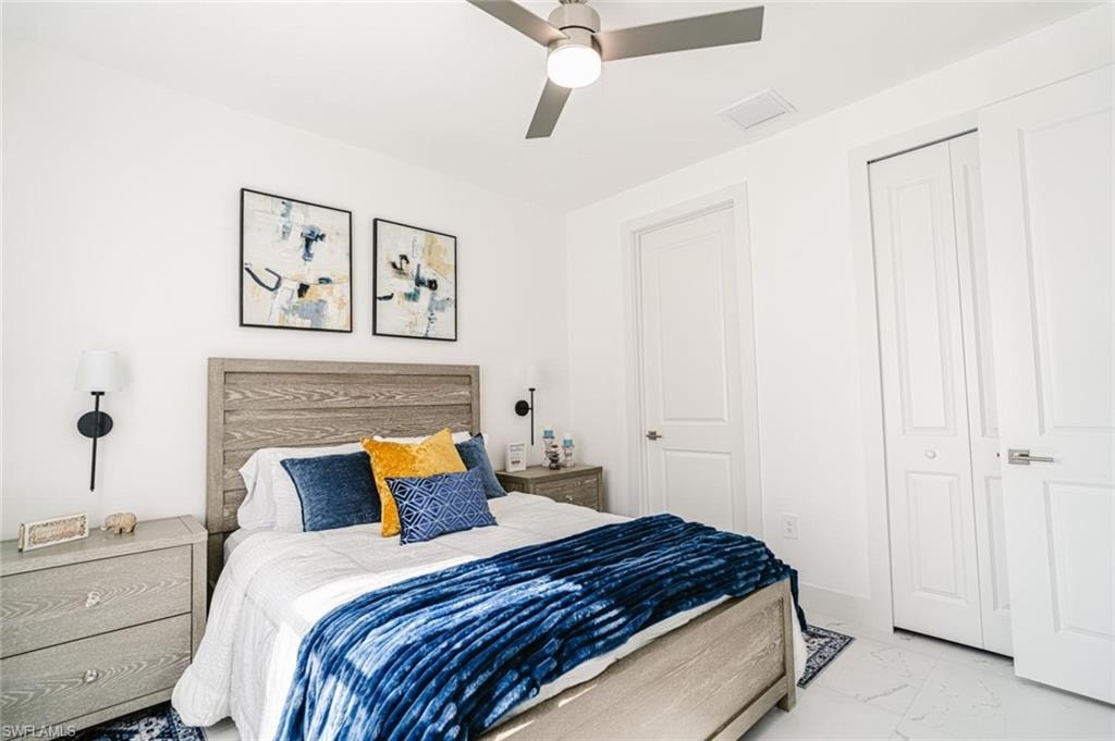 Bedroom featuring a wood-finish bed frame and headboard, white walls, and a ceiling fan with integrated lighting