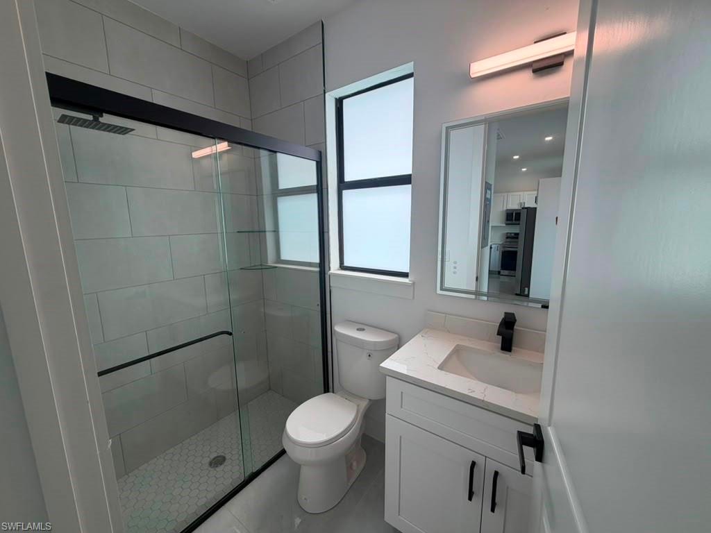 Modern bathroom featuring a glass-enclosed shower with black trim, a wall-mounted showerhead, and hexagonal floor tiling