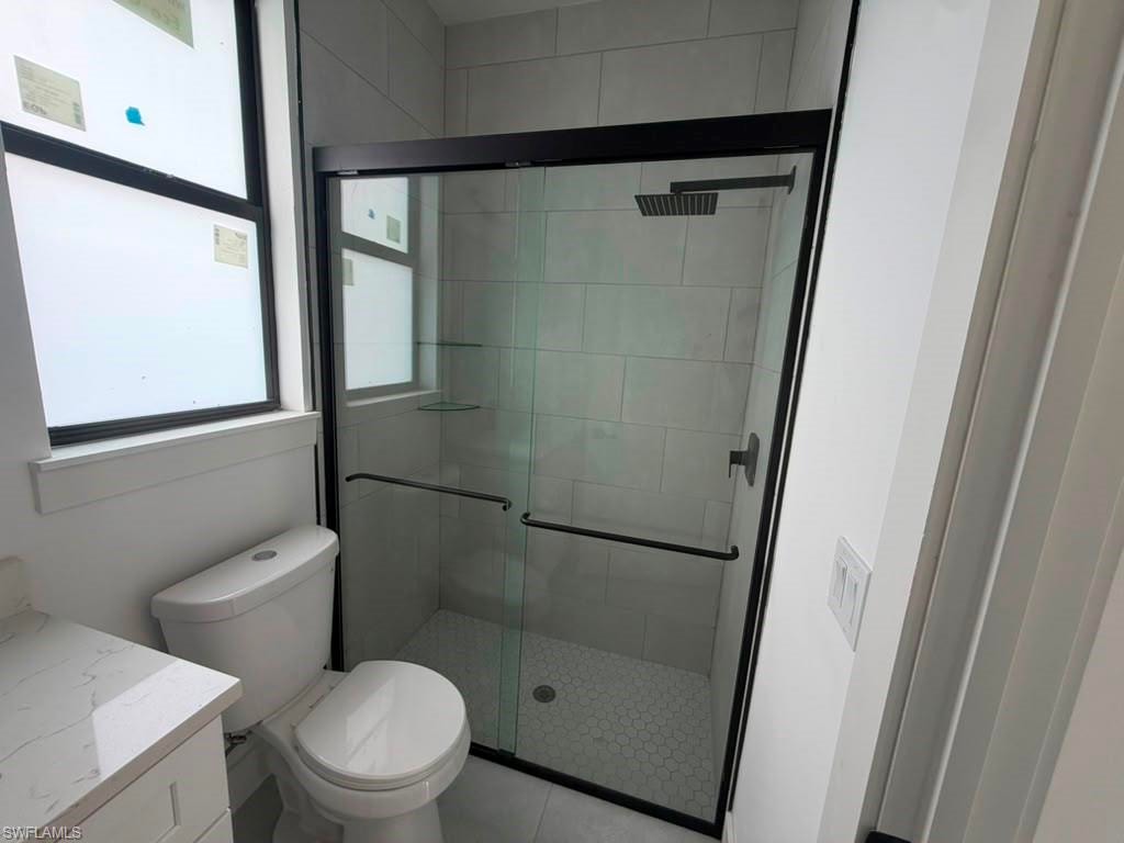 Modern bathroom featuring a glass-enclosed shower with matte black hardware, rectangular rain shower head, and hexagonal tile flooring