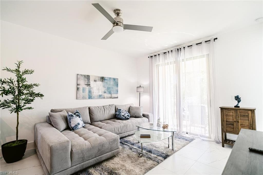 Bright living space featuring large-format tile flooring and a ceiling fan